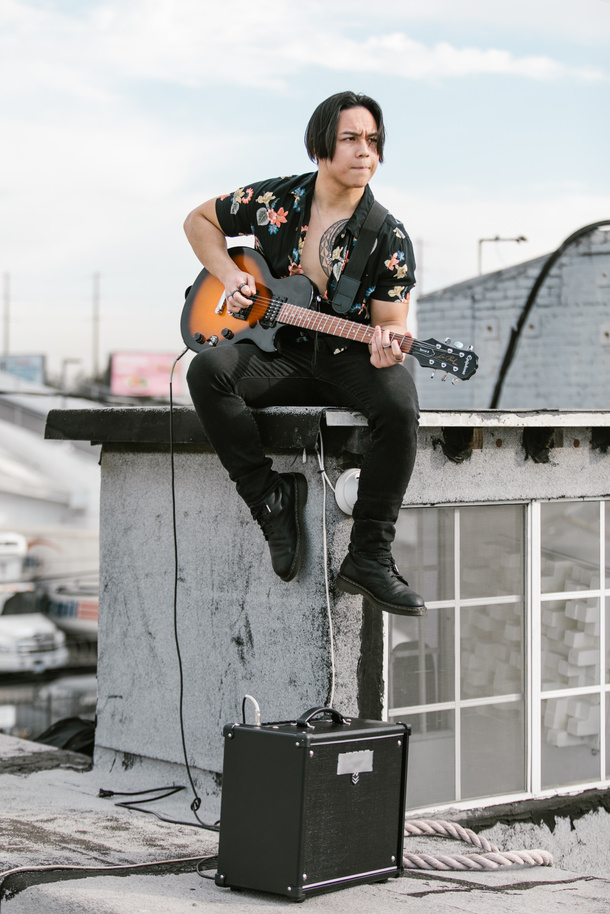 A Man in Black Floral Button Up Shirt Playing Guitar
